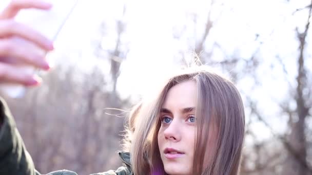 Headshot girl ubrany w take kurtka selfie w parku - Materiał filmowy, wideo