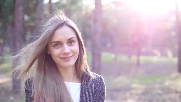 Gyönyörű fiatal nő áll a parkban - Felvétel, videó