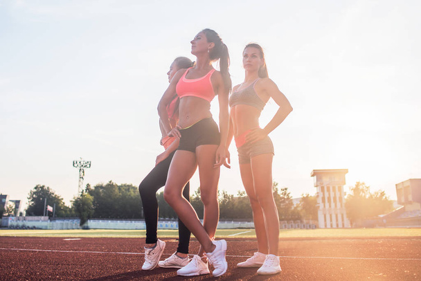 Grupo de jóvenes deportistas en forma de pie en el estadio de atletismo y posando
. - Foto, imagen