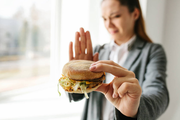 Uma jovem mostra um sinal com a mão significando que não há hambúrguer. Imagem conceitual de recusa de alimentação insalubre
. - Foto, Imagem