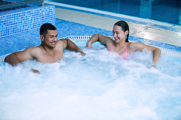 Веселая улыбающаяся пара в бассейне с пузырьками
 - Фото, изображение