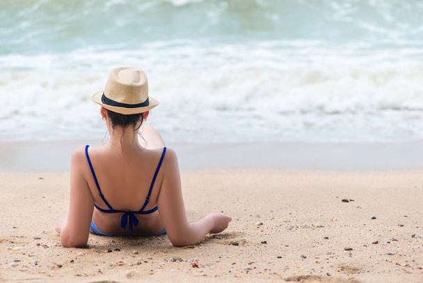 Женщина в бикини отдыхает на пляже и смотрит на море с ней
 - Фото, изображение