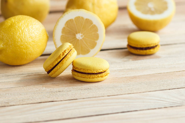 gelbe französische Macarons mit Zitronen auf dem Holzbrett - Foto, Bild