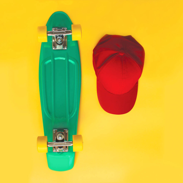 Fashion set. Skateboard and baseball cap over yellow background, - Фото, изображение