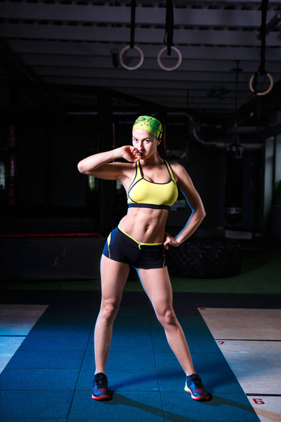 beautiful, strong, slender, in good physical shape in the gym doing exercises. Dressed in short shorts and tank top green, on the head bandage. - Foto, imagen