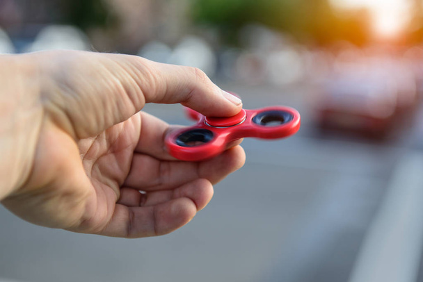 Man playing with fidget spinner stress relieving toy outdoors on city street - Fotografie, Obrázek