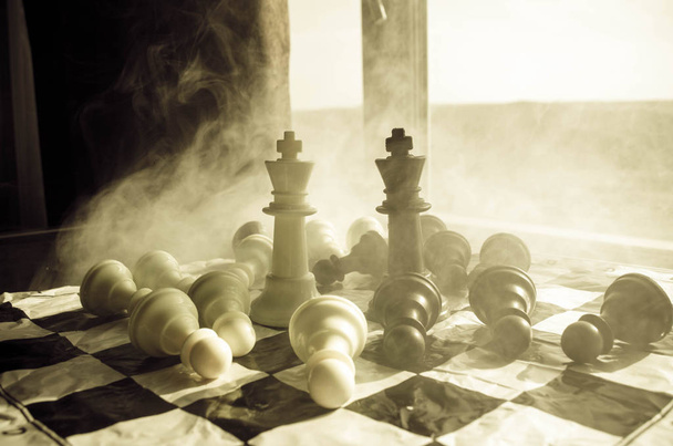 σκάκι παιχνίδι έννοια της επιχειρηματικές ιδέες και πρωτότ ιδέες ανταγωνισμού και στρατηγική. ΦΙΓΟΥΡΕΣ Σκακιου σε σκούρο φόντο με ομίχλη και τον καπνό και το παράθυρο με το φως του ήλιου. - Φωτογραφία, εικόνα