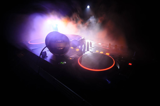 DJ Spinning, Mixing, and Scratching in a Night Club, Manos de dj ajustar varios controles de pista en la cubierta de dj, luces estroboscópicas y niebla, enfoque selectivo
 - Foto, imagen