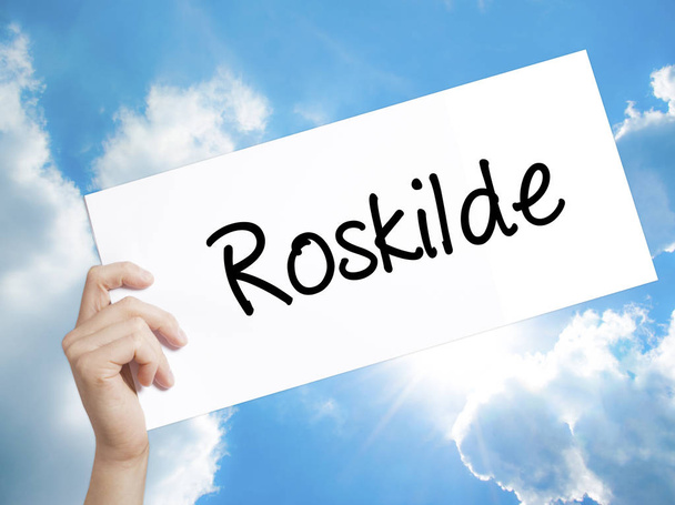 Roskilde jel a fehér papíron. Ember keze gazdaság papír szöveggel.  - Fotó, kép