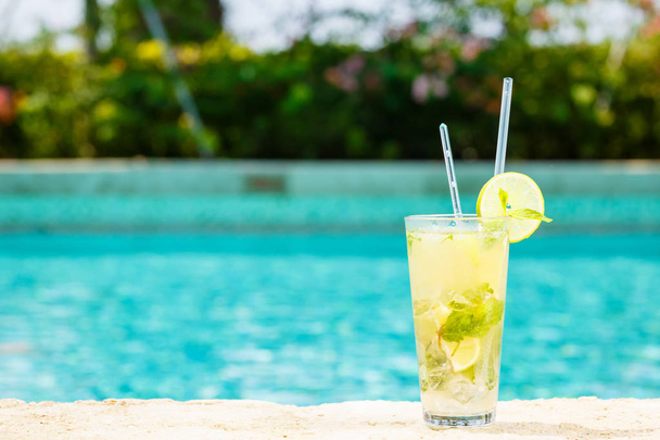 Mojito cocktail at the edge of a resort pool. Concept of luxury vacation. Outdoor pool background. Horizontal - Photo, Image