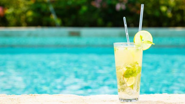Mojito cocktail at the edge of a resort pool. Concept of luxury vacation. Outdoor pool background. Horizontal, wide screen format - Photo, Image