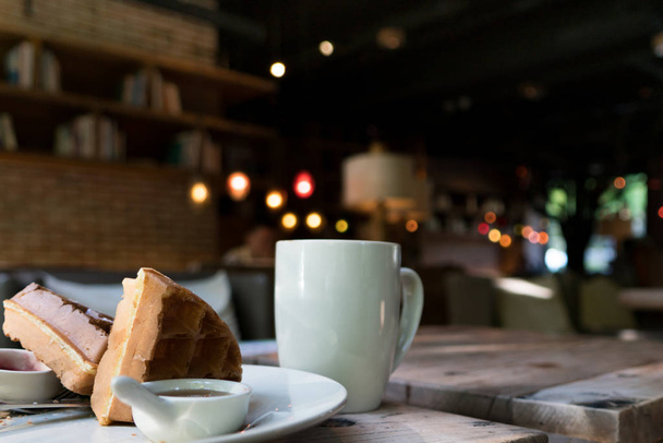 2 kawałki wafel biały filiżankę kawy na drewnianym stole - Zdjęcie, obraz