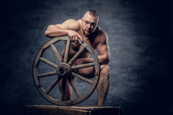 Man poseren met oude houten wiel  - Foto, afbeelding