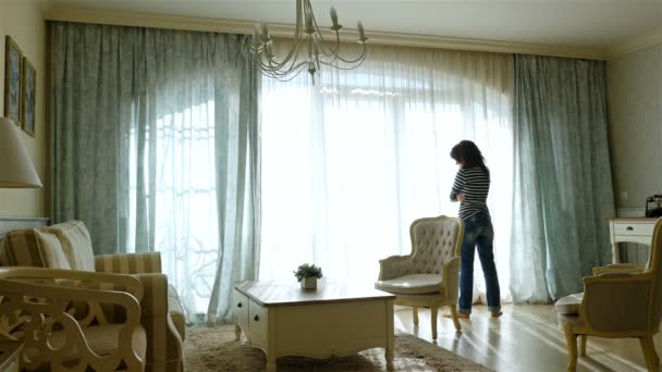 Ideges nő megy oda és vissza mentén a ablak-ból egy hangulatos apartman - Felvétel, videó