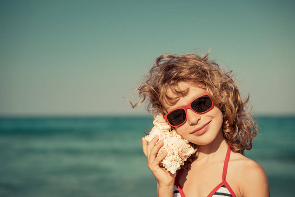 Ευτυχισμένο παιδί ακούει seashell στην παραλία - Φωτογραφία, εικόνα