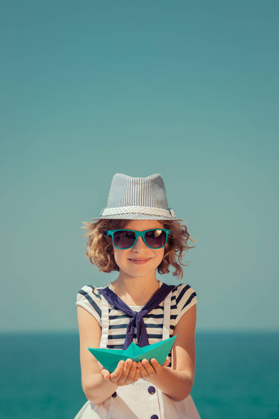 Child with paper sailing boat on summer vacation - Foto, imagen