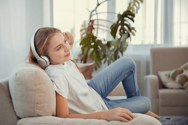 Красива дівчина-підліток зі смартфоном та навушниками, що слухають музику
. - Фото, зображення