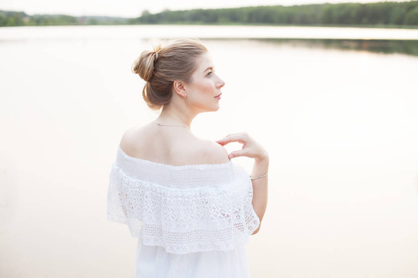 Tyttö valkoinen mekko poseeraa lähellä jokea
 - Valokuva, kuva