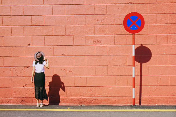Портрет молодої жінки з коричневим капелюхом. Модель позування і стоячи біля цегляної стіни і без знака паркування. Жінка і дорожній знак
. - Фото, зображення