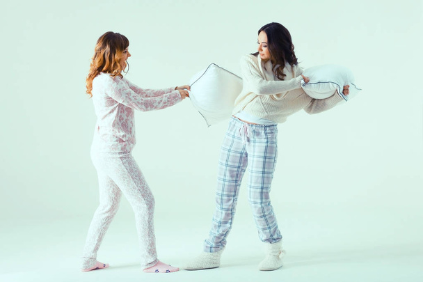 young women in pajamas fighting with pillows - Фото, зображення