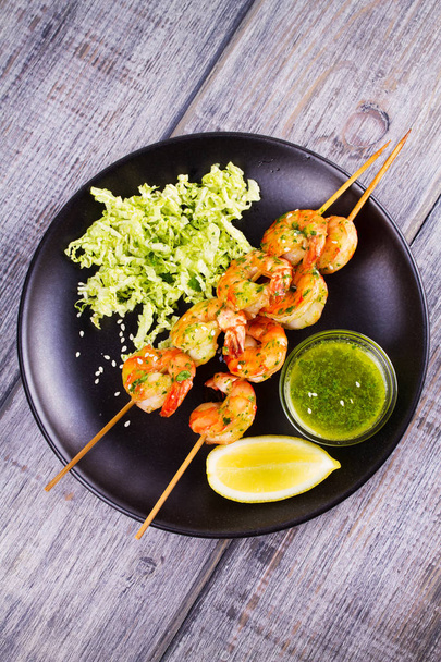 Cilantro grilled shrimps on skewers with sesame napa cabbage, green butter sauce and lemon - Zdjęcie, obraz
