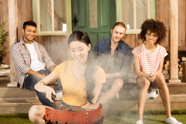 woman preparing barbecue while friends sitting - Photo, Image