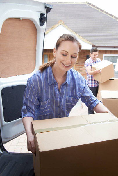 Young Couple Moving In To New Home  Unloading Removal Van - 写真・画像