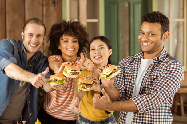 sorrindo amigos multiétnicos segurando hambúrgueres
 - Foto, Imagem