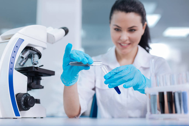 Positive delighted female scientist adding powder to reagent - Photo, Image
