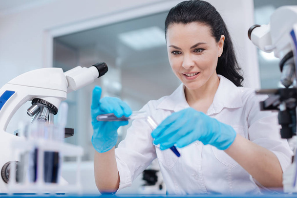 Attente vrouwelijke wetenschapper aandachtig kijken naar test-buizen - Foto, afbeelding