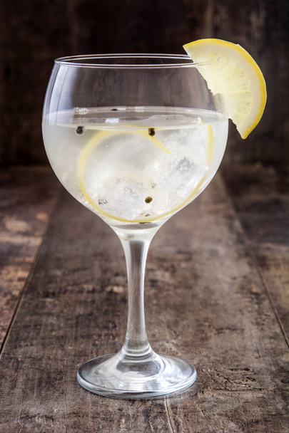 Ποτήρι τζιν τόνικ με λεμόνι σε φόντο ξύλινη - Φωτογραφία, εικόνα