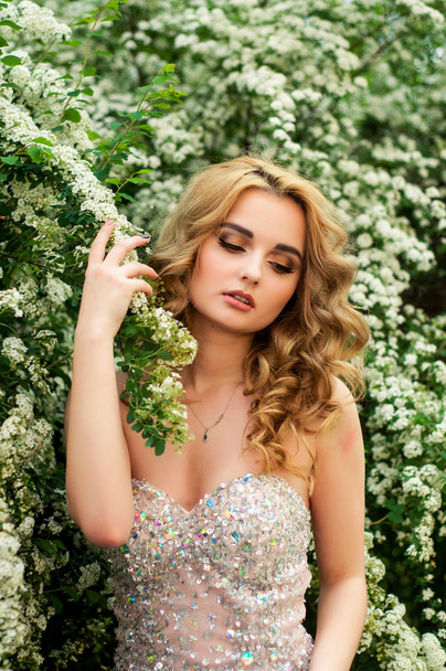 花の茂みや木々 の美しい笑顔間の途中の春のイブニング カクテル ドレスの女の子 - 写真・画像