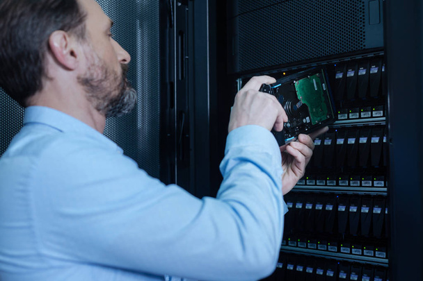 Serious IT administrator putting a rack server on its place - 写真・画像