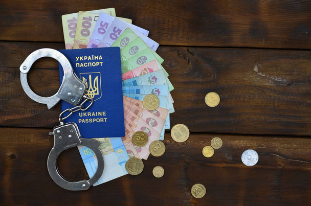 Een foto van een Oekraïense buitenlands paspoort, een zekere mate van Oekraïense geld en politie handboeien - Foto, afbeelding