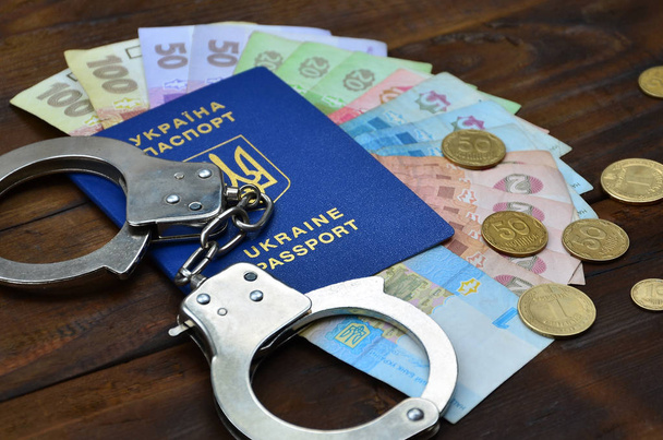 Una fotografia di un passaporto straniero ucraino, una certa quantità di denaro ucraino e manette della polizia
 - Foto, immagini
