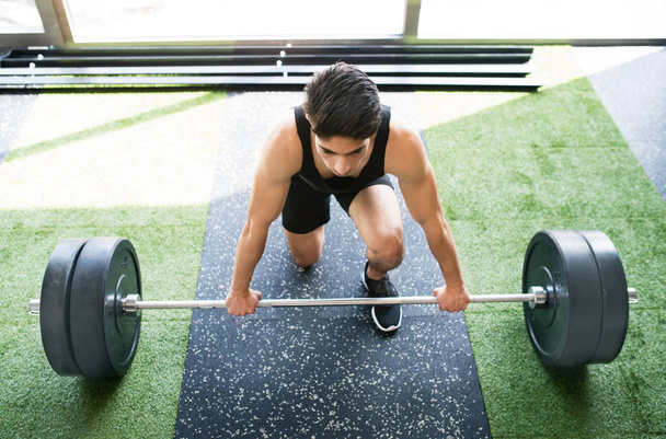Jeune homme hispanique en forme dans la salle de gym soulevant haltère lourde
 - Photo, image