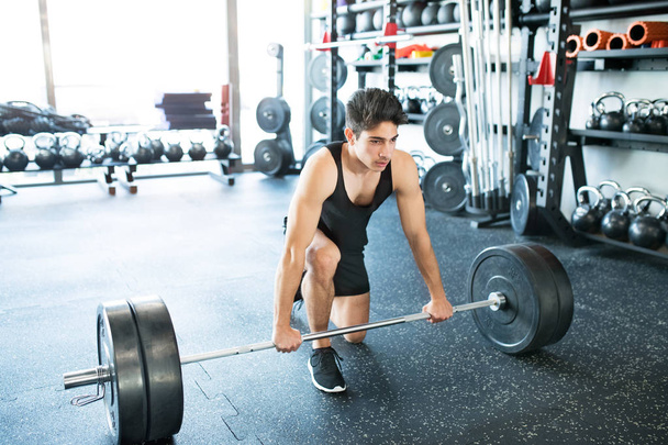 Young fit hispanic man in gym lifting heavy barbell - Φωτογραφία, εικόνα