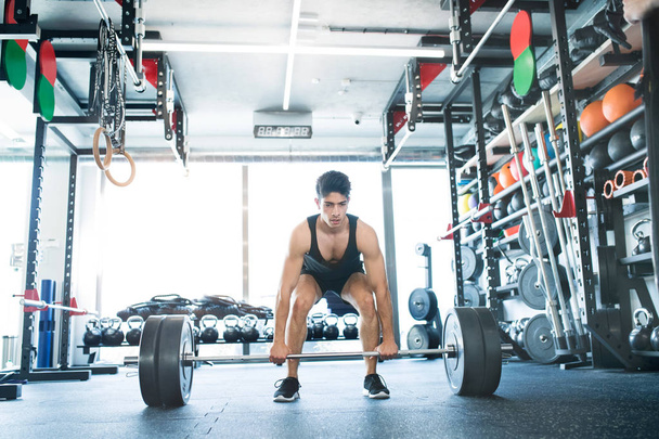 Young fit hispanic man in gym lifting heavy barbell - Foto, Imagem