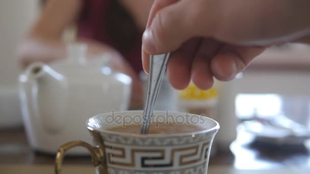 Férfi kézzel keverjük a cukor és tej egy csésze forró kávé vagy tea. Lassú mozgás közelről - Felvétel, videó