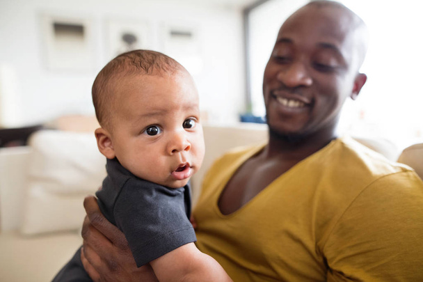 Young afro-american father holding his baby son in the arms - Foto, Bild
