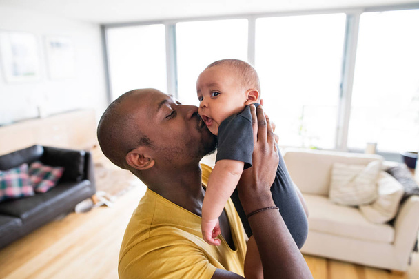 Young afro-american father holding his baby son in the arms - Foto, immagini