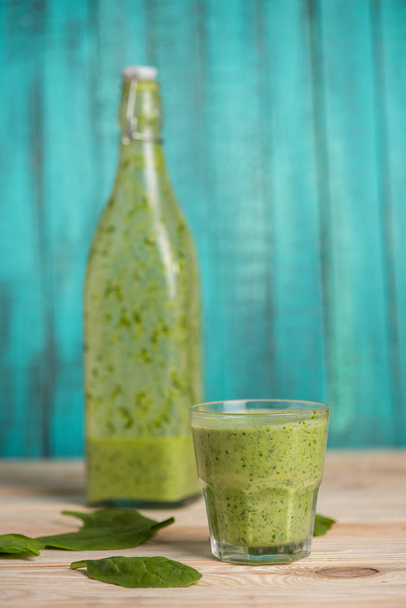 groene bladeren en smoothie in glas en fles - Foto, afbeelding