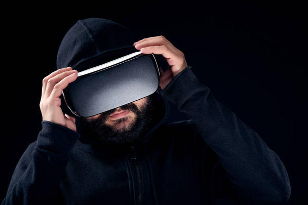 Young hipster bearded man wearing virtual reality goggles. Black background studio VR concept - Valokuva, kuva