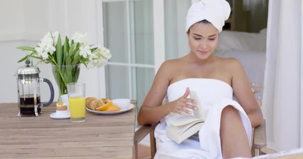 Woman in bath towel reading book at table - Footage, Video
