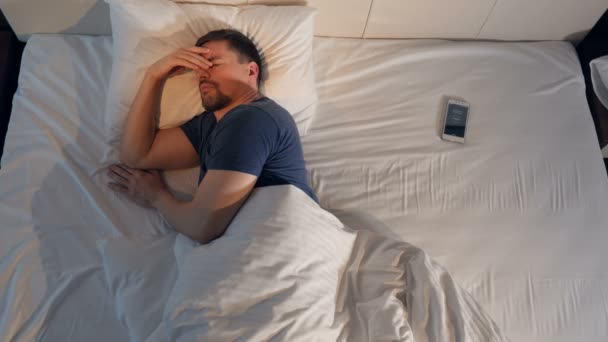 The sleeping man checking the time on the smartphone. 4K. - Video