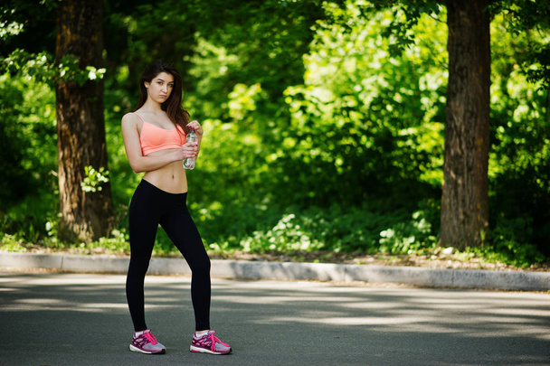 Fitness sport girl in sportswear posed at road in park with bott - Foto, afbeelding