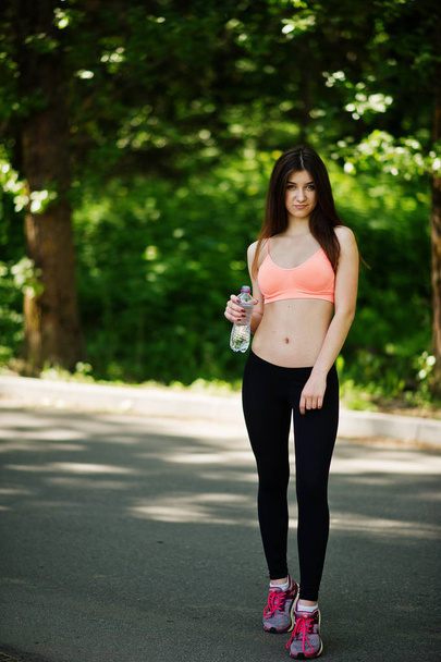 Fitness sport girl in sportswear posed at road in park with bott - Фото, изображение