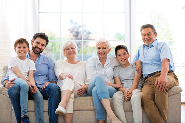 Hymyilevä perhe sohvalla
 - Valokuva, kuva