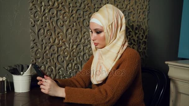 Egy modern arab nő kommunikál meg egy mobiltelefon, egy kávézóban - Felvétel, videó