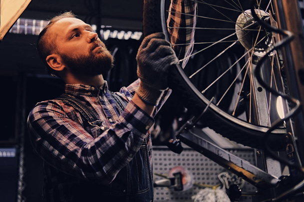 Mechanik naprawiający koła rowerowego  - Zdjęcie, obraz